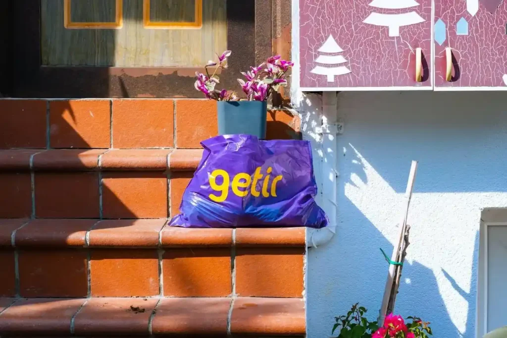 A Getir delivery bag placed on stairs with logo.