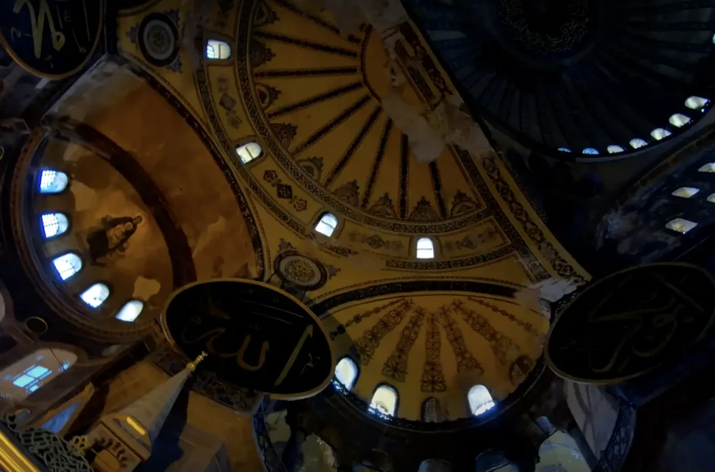 Interior view of the grand dome of Hagia Sophia, featuring Byzantine mosaics and architectural details.