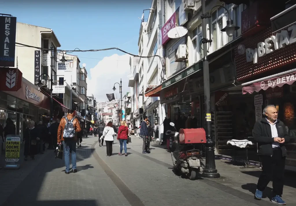 A view of Fahri Korutürk Street in Istanbul, with shops, cafes, and street life.