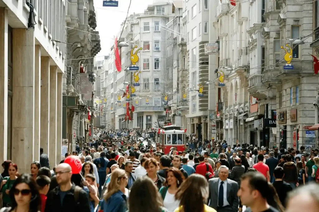 Crowds of people bustling along Istiklal Street in Istanbul, capturing the vibrant and lively atmosphere of it.