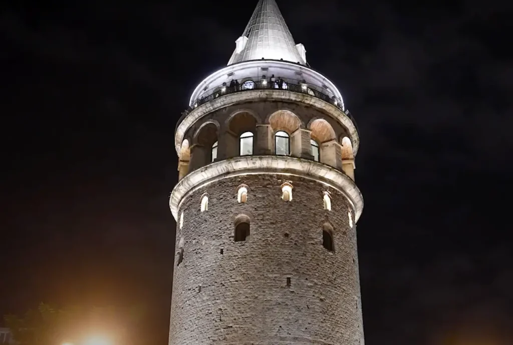 The Galata Tower brightly lit up at night, standing tall against the dark sky.