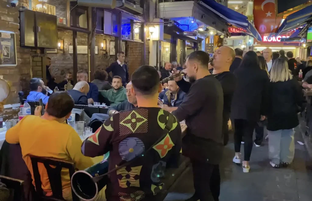 Nevizade Street bustling with activity at night, filled with bars, restaurants, and people.
