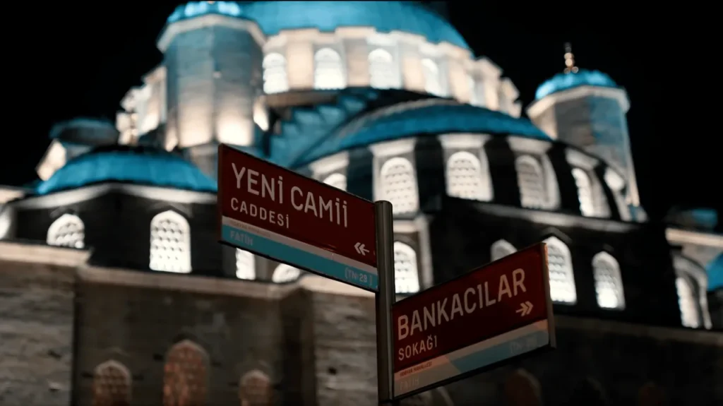 Yeni Mosque sign with the mosque’s domes and minarets visible in the background.