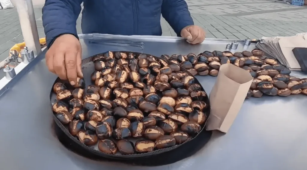 Close-up view of roasted chestnuts on a street vendor's trolley.