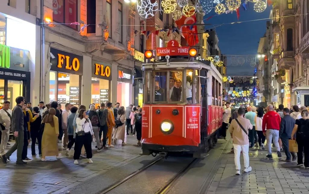 The historic red tram on Istiklal Street at night, illuminated by streetlights and city life.
