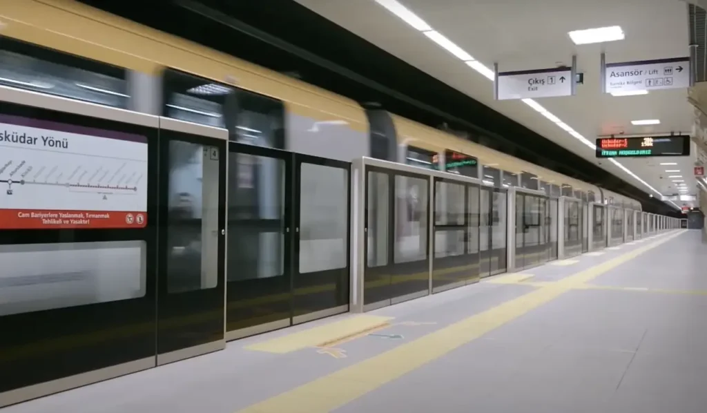 Platform of the M5 driverless metro line with a moving train.